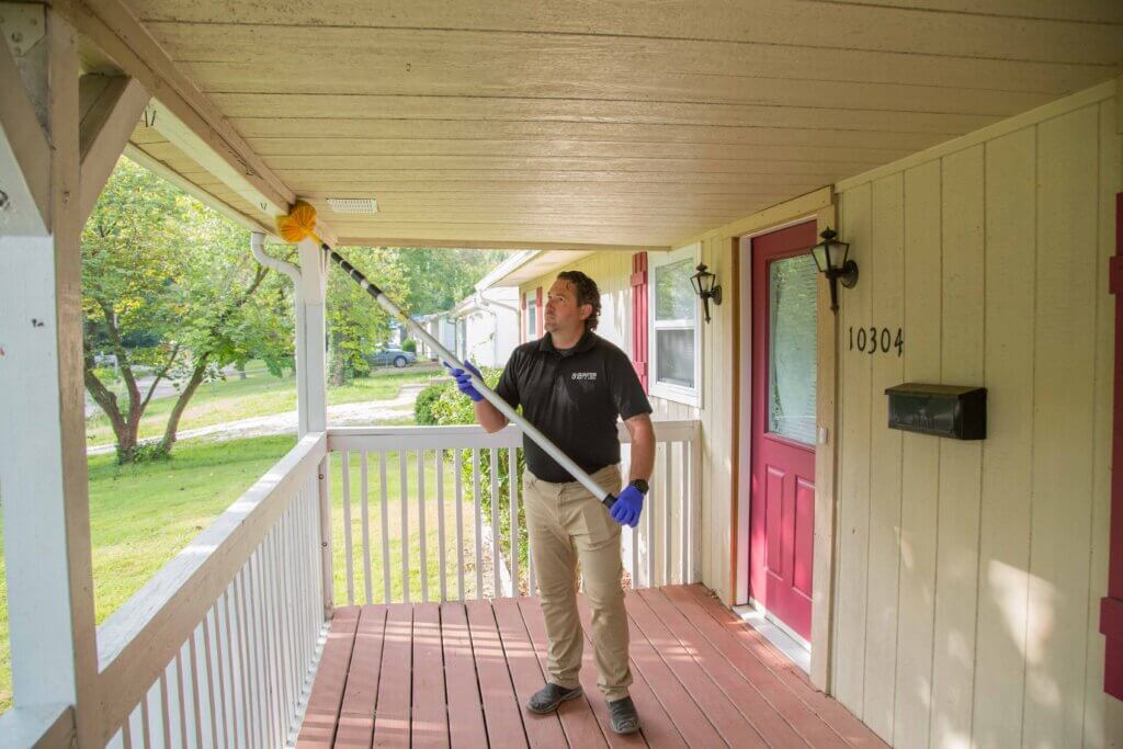 spider-duster A man keeping spiders out of his house.