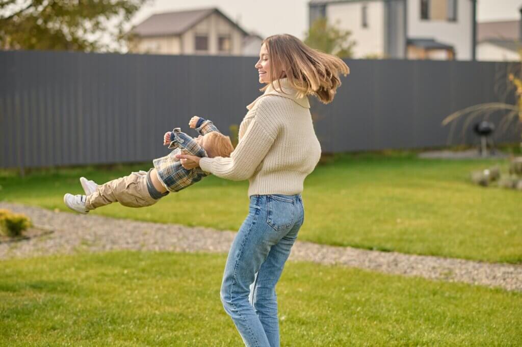 Woman playing with her child in her beautiful lawn.