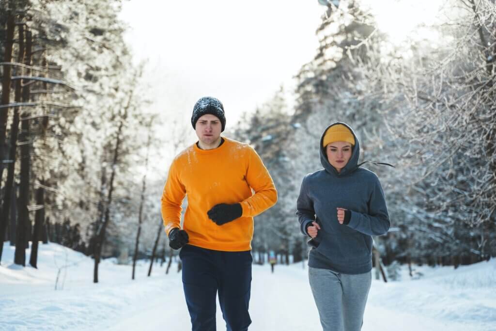 Sportive couple during winter jogging in city park.