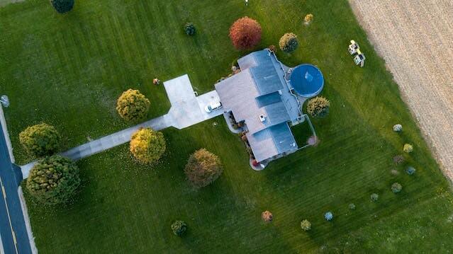 Aerial view of a rural home with colorful trees and a vast green lawn