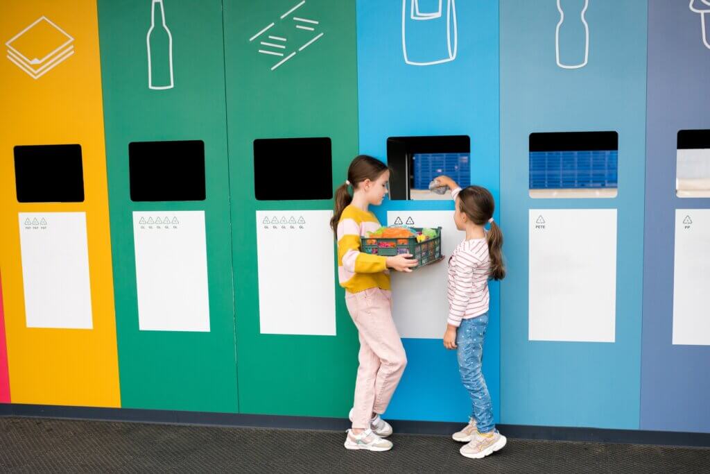 Girls taking out plastic trash in recycling centre. National recycling week.